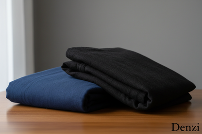 Create a 100% realistic vertical image showing two suits Navy blue and Black men’s unstitched cotton suits placed on a table in a neatly folded form. The fabric texture should be clearly visible with soft natural lighting. Keep the background simple and clean. Add the text ‘Denzi’ at the bottom-right corner in a minimal, elegant font in black color